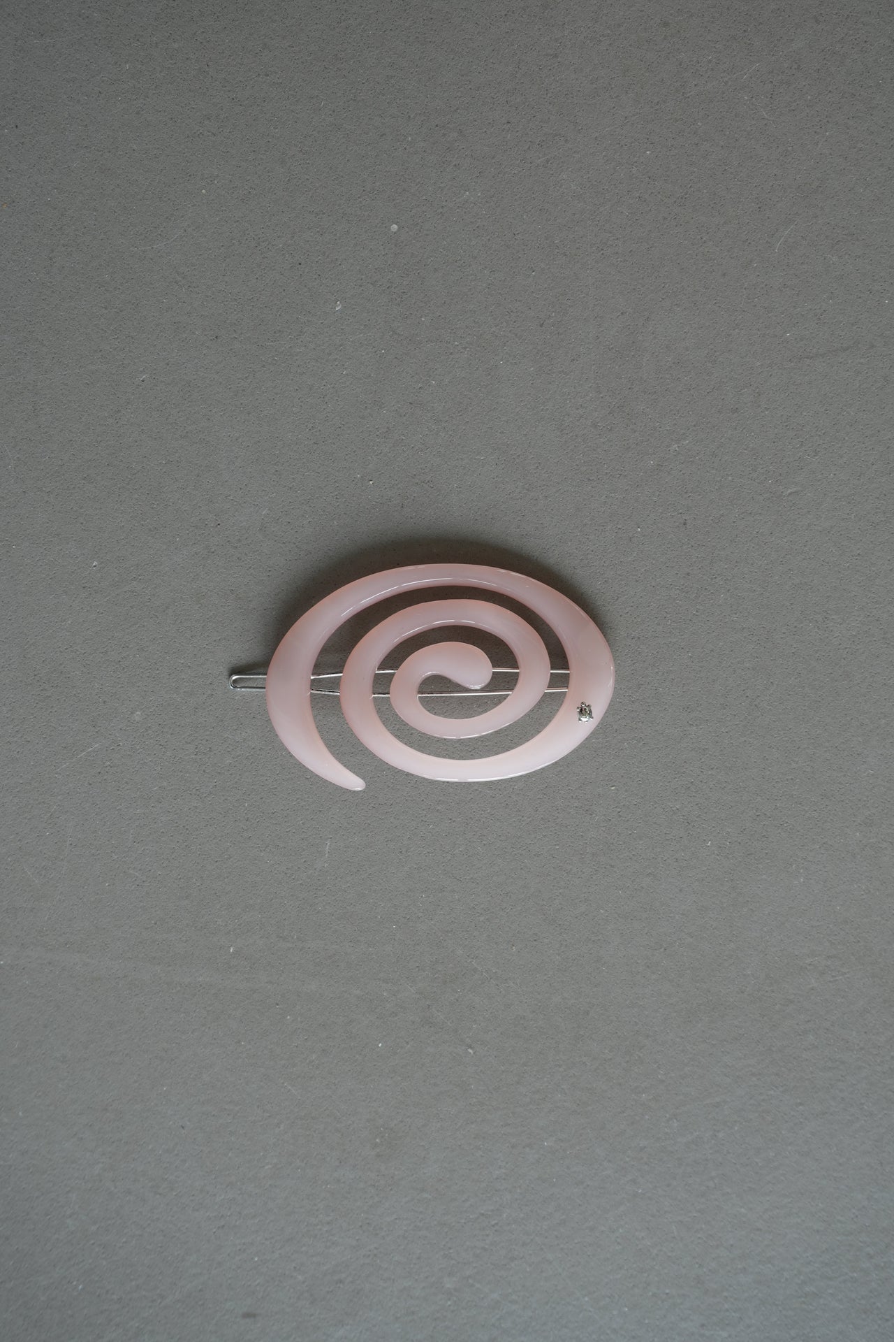 Pink spiral hair clip on a gray background