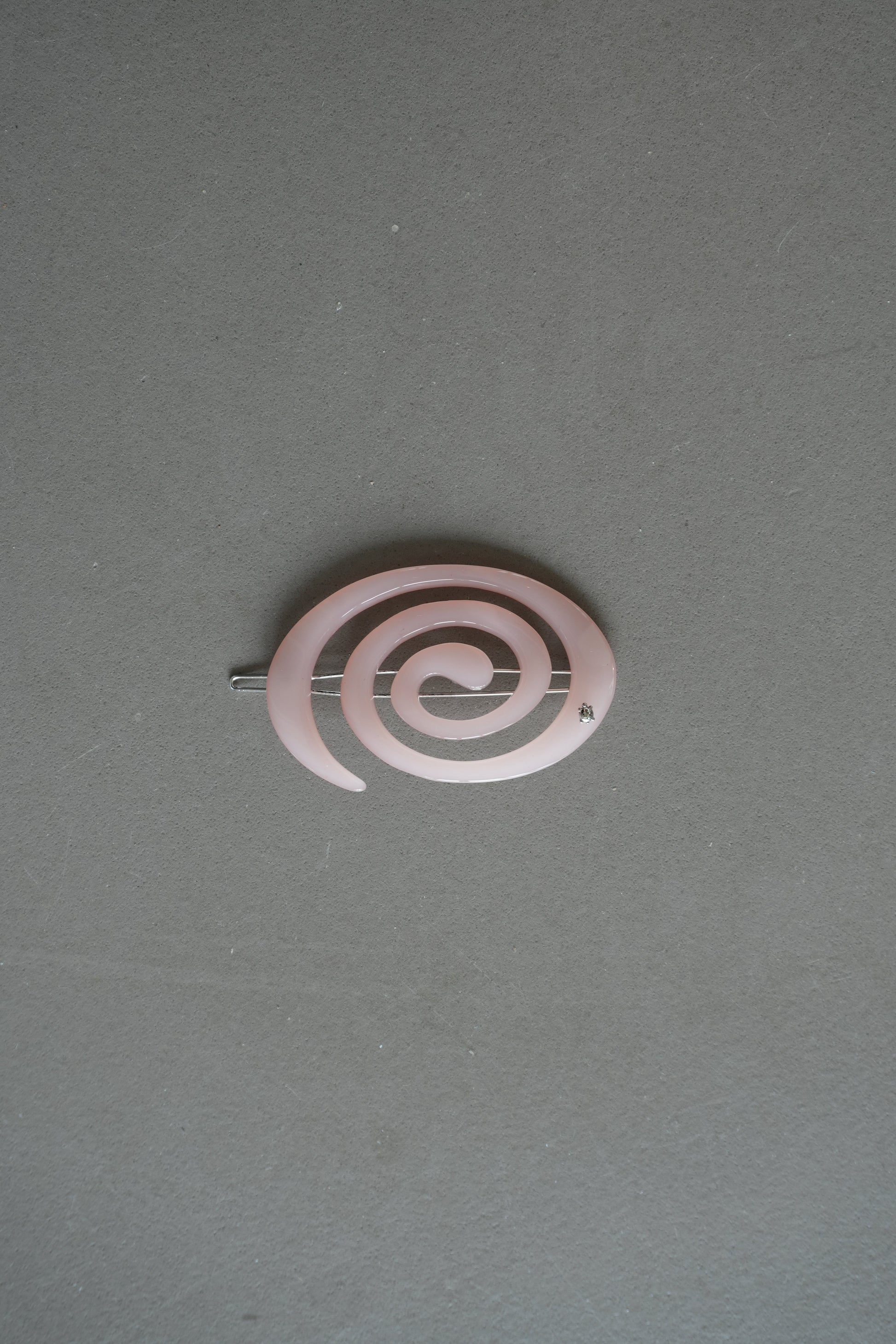 Pink spiral hair clip on a gray background